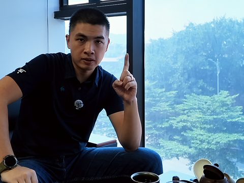 Đức ngồi bên bàn trà cạnh cửa kính lớn, giơ một ngón tay lên khi đang nói